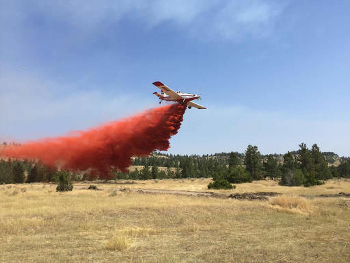 This photo, provided by the Montana Department of Natural Resources and Conversation, shows a plane dropping fire retardant on a fire line at the North Tullock wildfire near Hardin, Mont., Tuesday, Aug. 2, 2016. (Montana Department of Natural Resources and Conversation via AP)