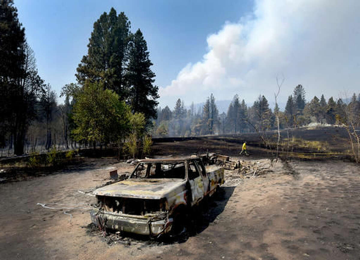 Tod McKay, spokesman for the Bitterroot National Forest, walks by a burned truck and shop at Dave Campbell's home in Judd Creek Hollow, Tuesday morning, Aug. 2, 2016, in Hamilton, Mont. Both were burned by a wildfire fire that blew up Sunday near Hamilton, however, his house survived the fire. "We're just trying to get people out of the way now," McKay told the Missoulian newspaper. "We can rebuild homes. We need to get people out of this area." (Kurt Wilson/The Missoulian via AP)