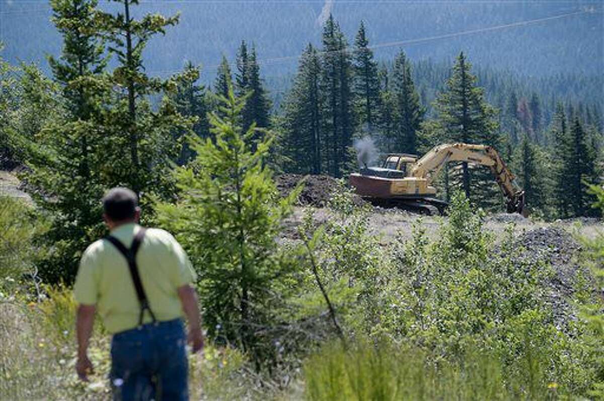 ADVANCE FOR THE WEEKEND OF AUG. 6-7 AND THEREAFTER - In a July 14, 2016 photo, Ted Salka walks past a worker making repairs on his property in North Bonneville, Wash. Salka's plans to sell some of his land to the U.S. Forest Service has frustrated local officials. (Amanda Cowan/The Columbian via AP)