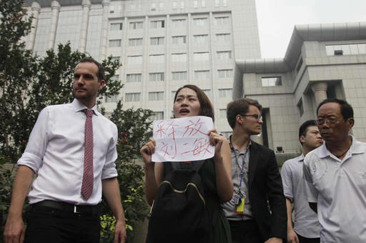 In this Monday, Aug. 1, 2016 photo, Li Wenzu, center, wife of imprisoned lawyer Wang Quanzhang, holds a paper that reads "Release Liu Ermin" stage a protest next to members of foreign diplomats and supporters of a prominent Chinese human rights lawyer and activists outside the Tianjin No. 2 Intermediate People's Court in northern China's Tianjin Municipality. In halting televised confessions and emotional courtroom testimony, Chinese lawyers and activists held in a government crackdown have intoned the same ominous refrain: Shadowy foreign forces are funding, directing and encouraging activities bent on destabilizing China's government and smearing its reputation. (AP Photo/Gerry Shih)