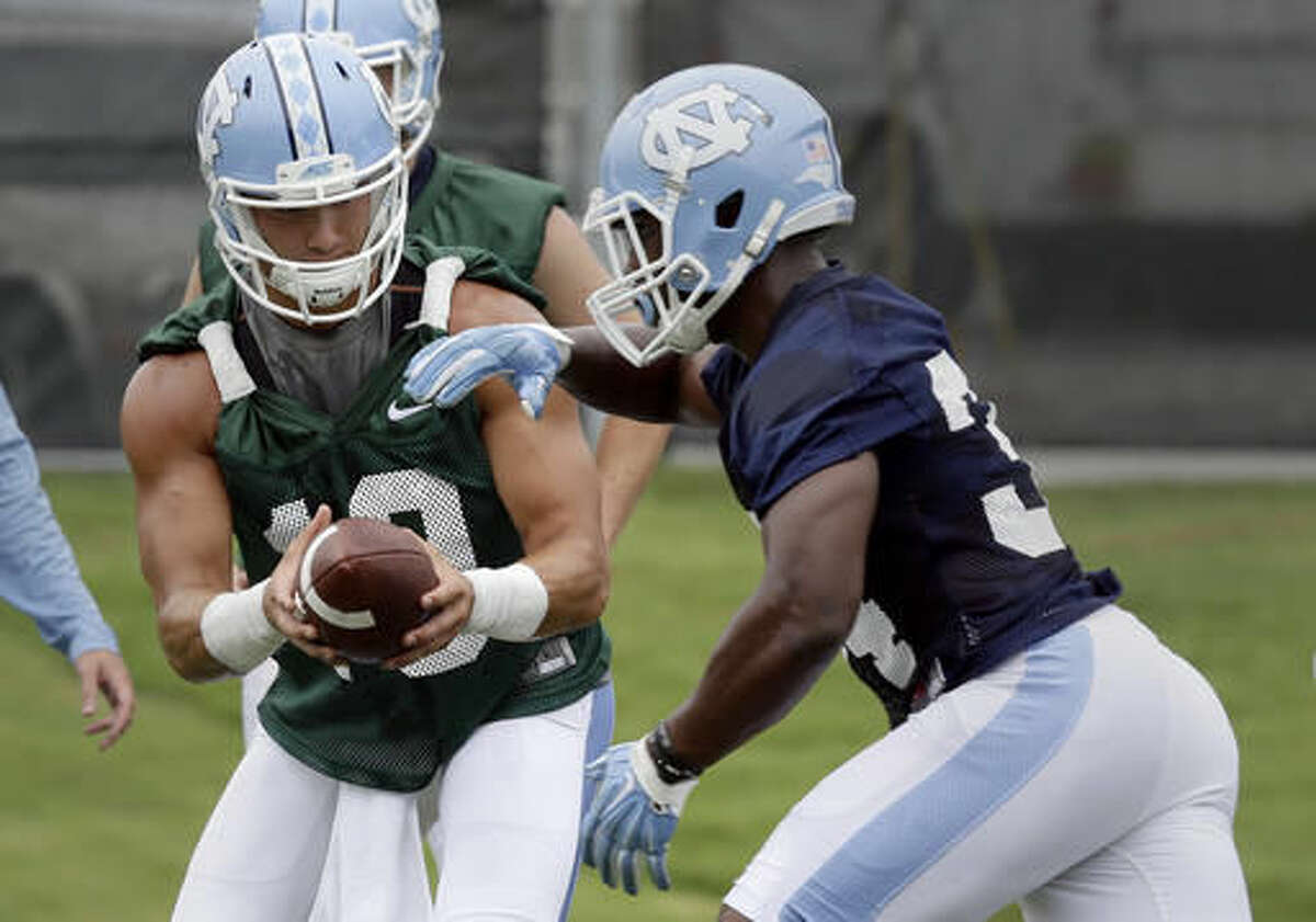 North Carolina quarterback Mitch Trubisky, left, hands the ball off to tailback Elijah Hood during the team's first NCAA college football practice of the season in Chapel Hill, N.C., Friday, Aug. 5, 2016. (AP Photo/Gerry Broome)