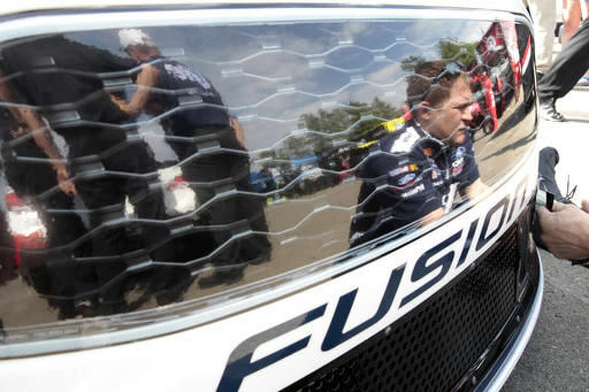 Crew member Jerry Kelley, right, is reflected in the paint as he works on the race car of Brad Keselowski (2) in the garage area at Watkins Glen International racetrack before practice for Sunday's NASCAR Sprint Cup Series auto race Friday, Aug. 5, 2016, in Watkins Glen, N.Y. (AP Photo/Mel Evans)