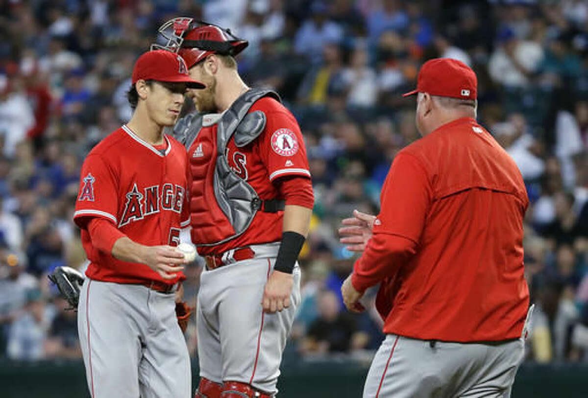 Los Angeles Angels starting pitcher Tim Lincecum, left, walks past catcher Jett Bandy as he is pulled in the fourth inning of a baseball game against the Seattle Mariners by manager Mike Scioscia, right, Friday, Aug. 5, 2016, in Seattle. (AP Photo/Ted S. Warren)