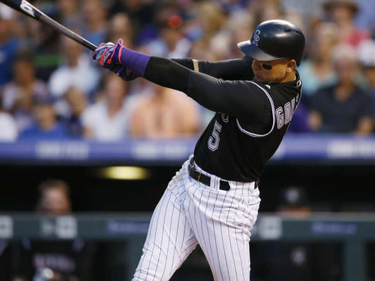 Colorado Rockies' Carlos Gonzalez follows through with his swing after connecting for an RBI-double off Miami Marlins starting pitcher Andrew Cashner in the sixth inning of a baseball game Saturday, Aug. 6, 2016, in Denver. (AP Photo/David Zalubowski)