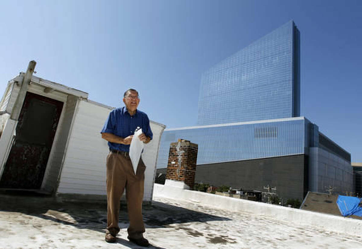 FILE - In this Aug. 27, 2014, file photo, piano tuner Charlie Birnbaum of Hammonton, N.J., stands on the roof of the three-story house where he was raised, a couple blocks from the site where the 47-story Revel Casino Hotel was built in Atlantic City, N.J. New Jersey Superior Court Judge Julio Mendez ruled Friday, Aug. 5, 2016, that the Casino Reinvestment Development Authority's yearslong effort to condemn the house to assemble land for a tourism district is an abuse of eminent domain power and exceeds the agency's authority. (AP Photo/Mel Evans, File)
