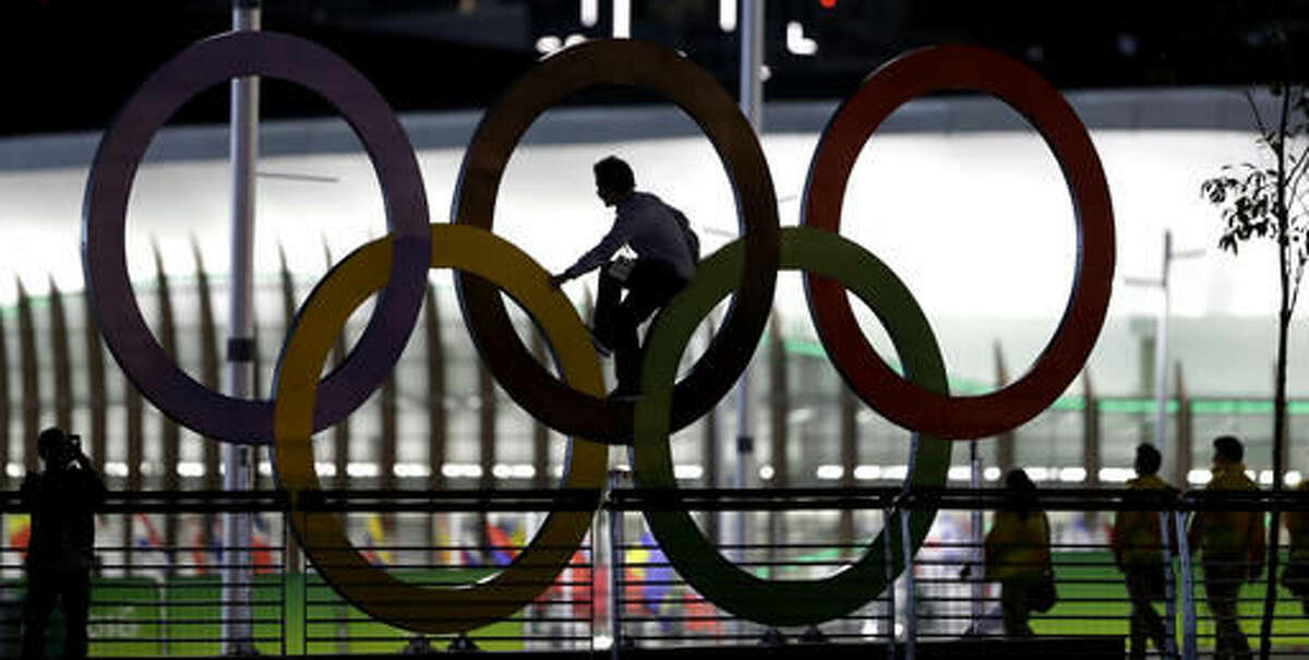 A man climbs on the Olympic rings near the basketball venue in the Olympic park on th eve before the opening ceremony of the 2016 Summer Olympics in Rio de Janeiro, Brazil, Thursday, Aug. 4, 2016. (AP Photo/Eric Gay)
