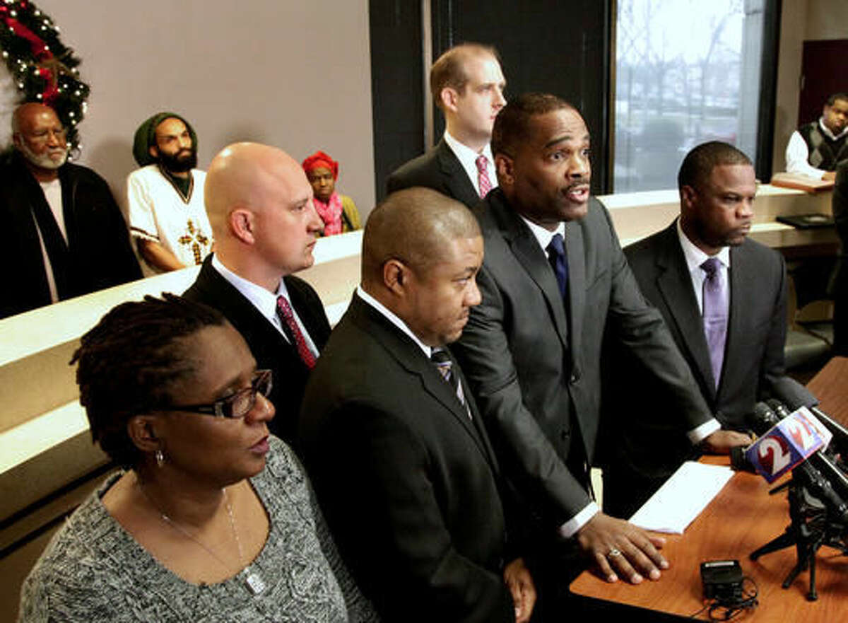 FILE - In this Dec. 16, 2014, file photo, in the front row from left to right, John Crawford III's mother Tressa Sherrod, attorney Michael Wright, Crawford's father John H. Crawford Jr. and attorney Shean Williams discuss the filing of a federal civil rights and negligence lawsuit during a news conference in Dayton, Ohio. Two years after a white policeman fatally shot John Crawford III on Aug. 5, 2014, in a Wal-Mart store in the Dayton suburb of Beavercreek, Ohio, as Crawford carried an air rifle picked up from a store shelf, the U.S. Justice Department has yet to conclude its investigation and won't say why, despite the family's push for an update. (Lisa Powell/Dayton Daily News via AP, File)