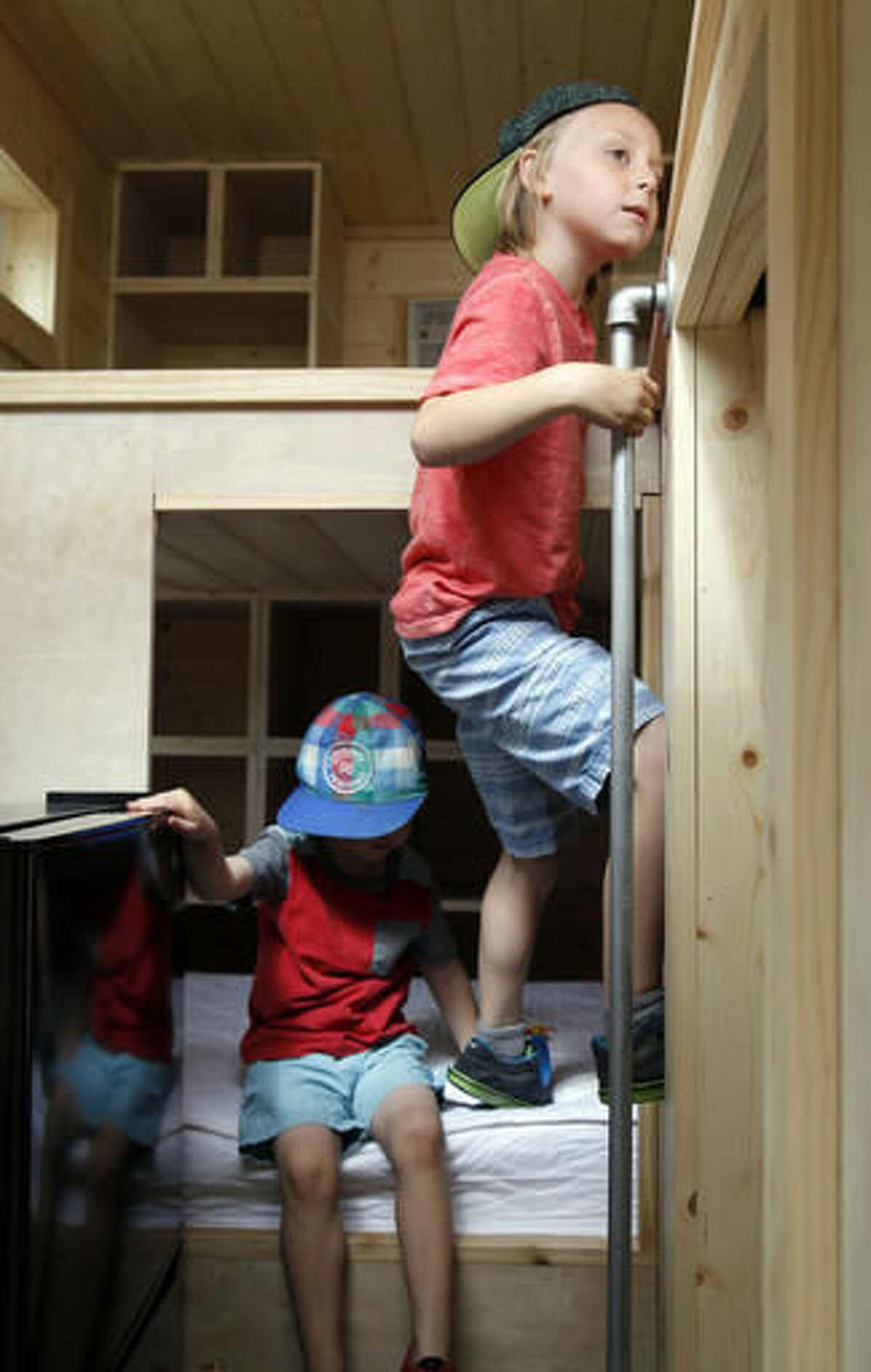 In this July 16, 2016, photo, Drake Darger, right, and Aiden Garder, play in a model tiny house at a display outside the Cabela's in Lehi, Utah. The Tiny Home movement is a worldwide change in the way people use their living spaces. The Daily Herald reports it is becoming a trend in Utah County. (Chris Samuels/The Daily Herald via AP)