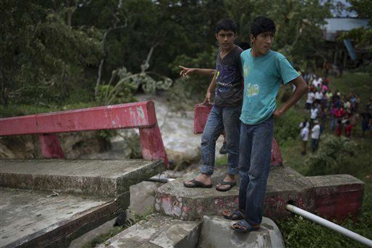 Dos hombres sobre un trozo de puente dañado por el huracán Earl en el barrio de Arroyito, en Melchor de Mencos, Guatemala, en la frontera con Belize, el jueves 4 de agosto de 2016. (AP Foto/Luis Soto)