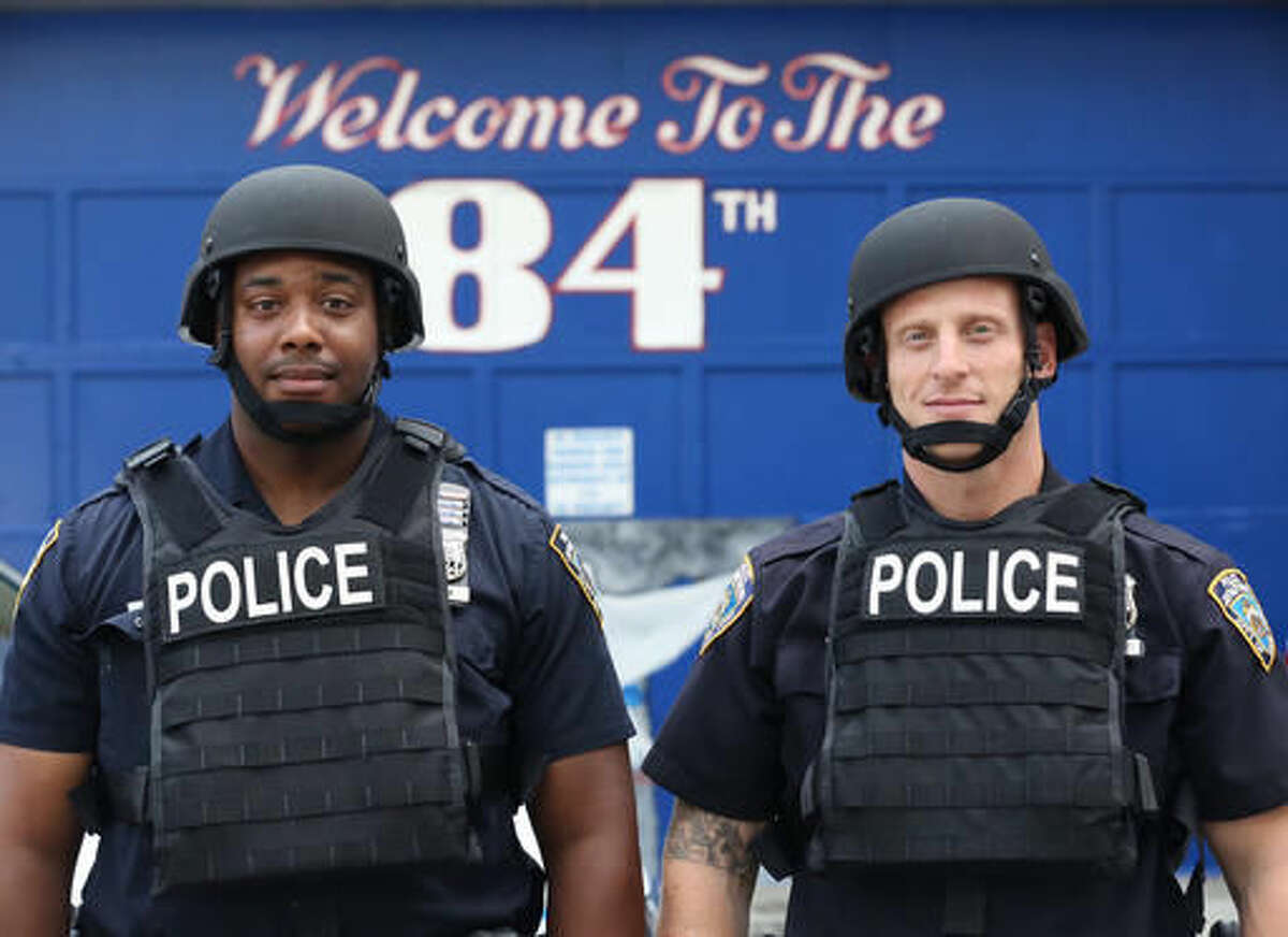 In this July 25, 2016 photo provided by the New York Police Department, Jamal Skinner, left, and Evan Aronowitz, patrol officers with the 84th Precint, model ballistic body armor and helmets during a news conference at the 84th Precinct in the Brooklyn borough of New York. The NYPD plans to distribute 20,000 helmets and 6,000 vests before the end of the year. The equipment will be issued to uniformed patrol officers at a time when the NYPD is also encouraging them to be more approachable to law-abiding citizens. (NYPD via AP)