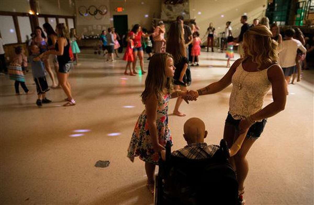 FOR RELEASE SATURDAY, AUGUST 6, 2016, AT 12:01 A.M. CDT.- BrookLynne Peterson and Kayla Streich, a counselor and former camper, dance with Jaxson Rold during camp CoHoLo at the Eastern Nebraska 4-H Center Tuesday, July 26, 2016, in Gretna, Neb. (Matt Dixon/The World-Herald via AP)
