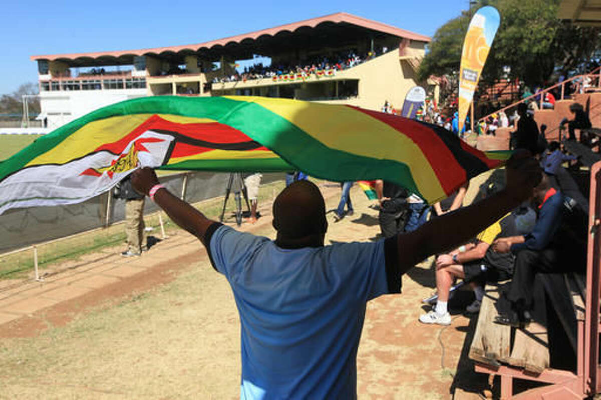 A man carries the Zimbabwean flag, during the 36th over of the test cricket match between New Zealand and Zimbabwe, at Queens Sports Club in Bulawayo, Zimbabwe, Saturday, Aug. 6, 2016. (AP Photo/Tsvangirayi Mukwazhi)