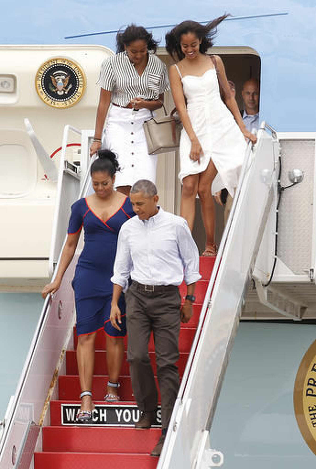 President Barack Obama and first lady Michelle Obama exit Air Force One followed by daughters Sasha, left, and Malia, right, at the Cape Cod Coast Guard Station in Bourne, Mass., Saturday, Aug. 6, 2016, en route to Martha's Vineyard. (AP Photo/Stew Milne)