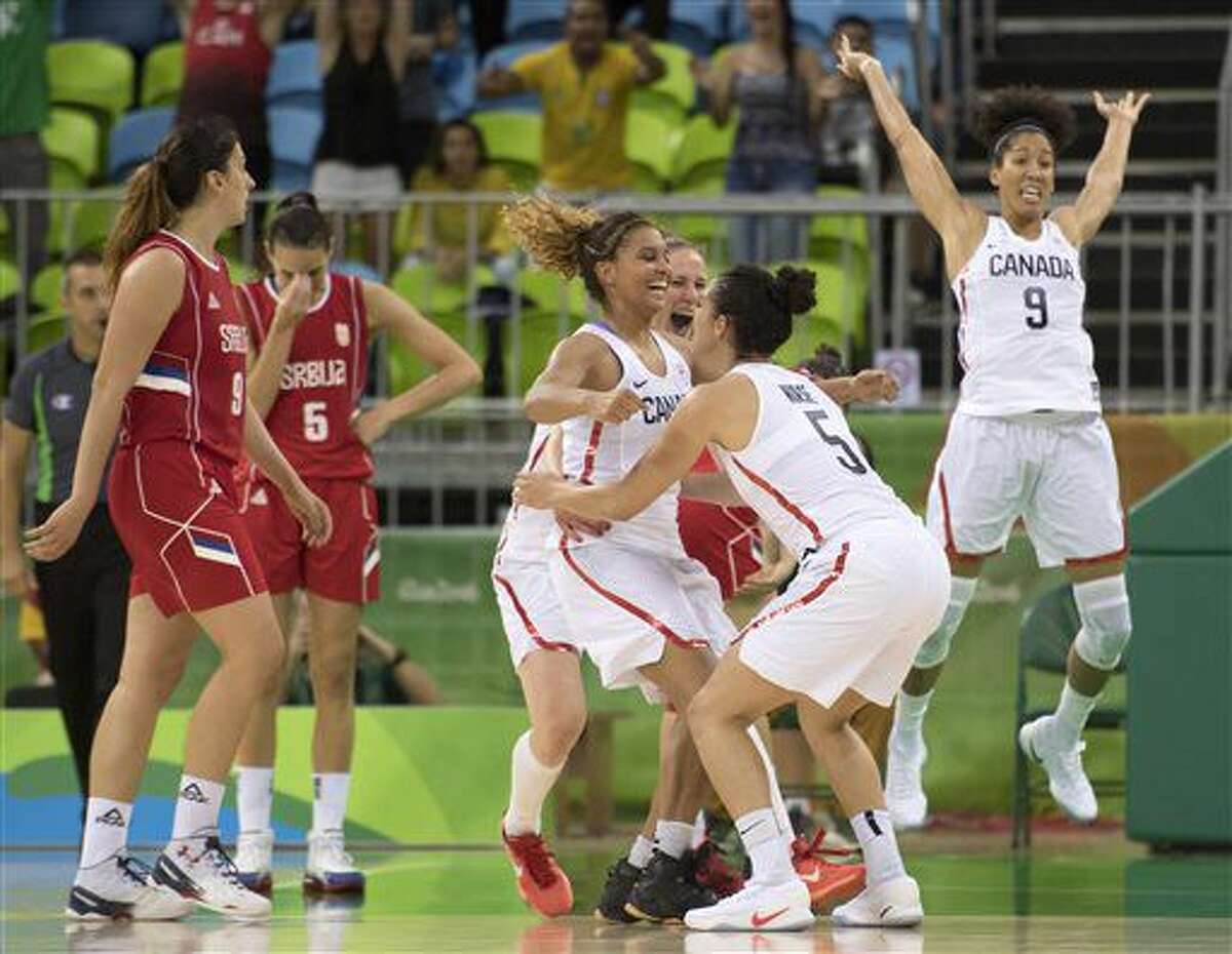 Serbia's Sonja Petroic (5) and Jelena Miovanovic (9) react as Canada's Miah-Marie Langlois, left center, jumps into the arms of teammate Kia Nurse (5) and Miranda Ayim (9) leaps to celebrate winning their preliminary round match at the 2016 Summer Olympics Monday Aug. 8, 2016, in Rio de Janeiro, Brazil. (Frank Gunn/The Canadian Press via AP)