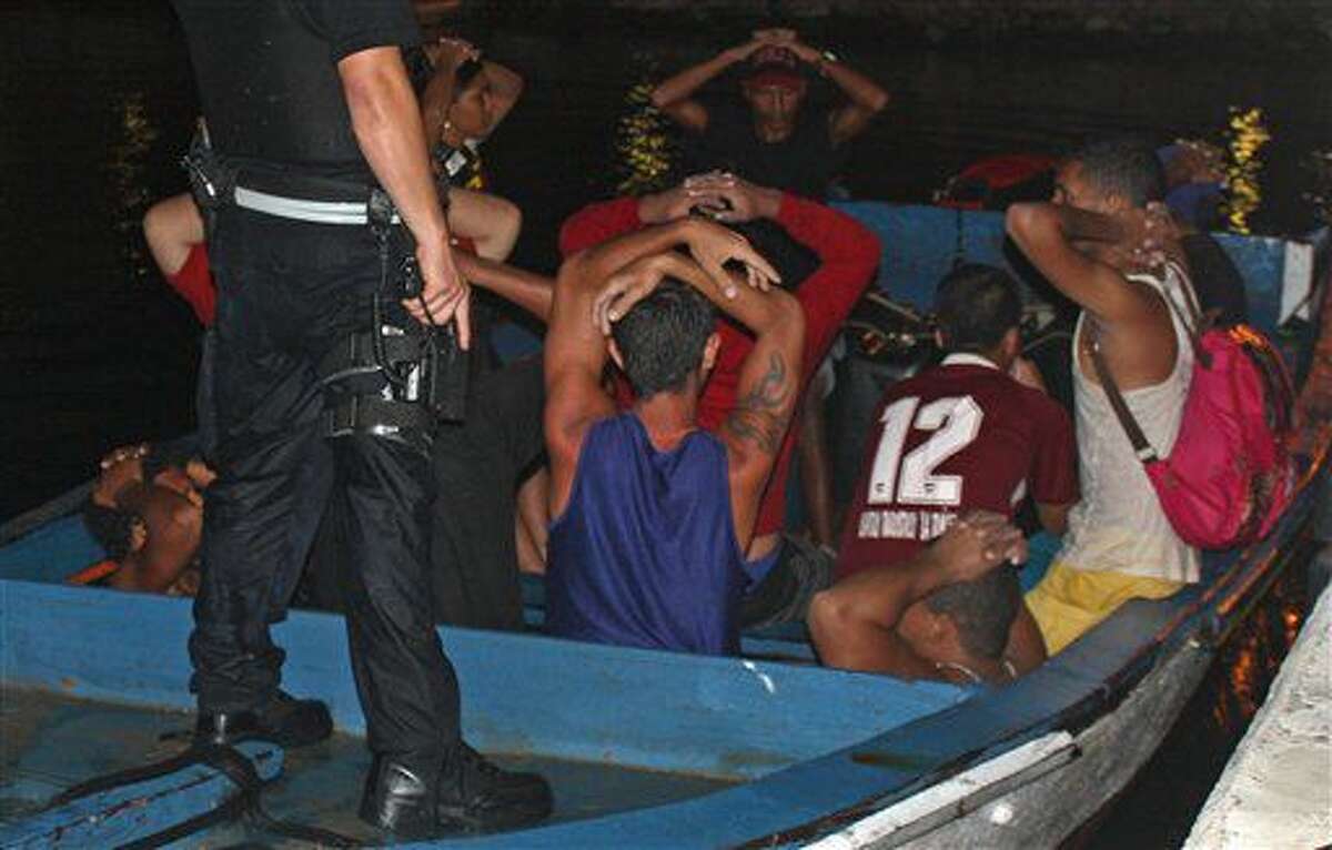 En esta fotografía del sábado 6 de agosto de 2016, autoridades detienen una embarcación en la que viajaban 20 migrantes venezolanos y uno colombiano en la subestación de la guardia costera en Parera, Curazao. La policía decomisó contrabando como cigarrillos y municiones y detuvo a todas las personas que viajaban a bordo porque presuntamente intentaban ingresar ilegalmente en Curazao. El portavoz de la Guardia Costera, Roderick Gouverneur, dijo que todos los migrantes estaban detenidos el lunes. (Foto de Roderick N. Gouverneur/Guardia Costera Caribeña Holandesa)