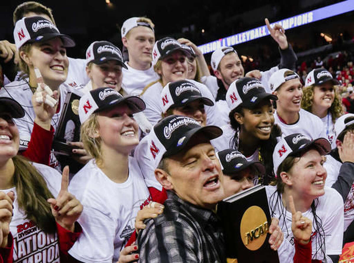 FILE - In this Dec. 19, 2015, file photo, Nebraska NCAA college volleyball coach John Cook, his players and staff, pose for a photo in Omaha, Neb., with the national championship trophy after defeating Texas for the title. During Media Day on Monday, Aug. 8, 2015, coach Cook and his players are expected to discuss their hopes of winning a second straight national championship. (AP Photo/Nati Harnik, File)