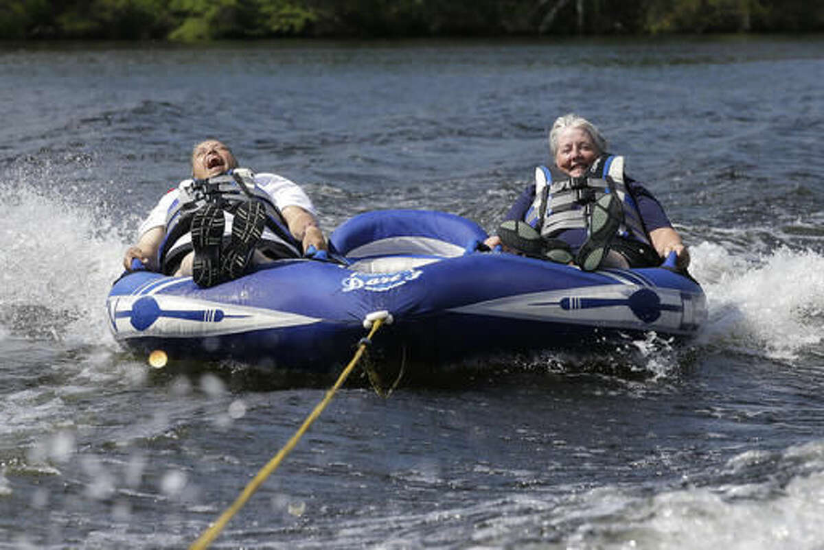 In this Tuesday, July 19, 2016 photo U.S. Navy veteran Raquel Ardin, of North Hartland, Vt., left, who suffered a broken neck while serving in the Navy, laughs while riding an inflatable craft with her partner Lynda Deforge, right, also of North Hartland, during a rehabilitation clinic in Coventry, R.I. The Providence VA Medical Center hosted the four-day clinic for veterans with spinal cord injuries, amputations, visual impairments, neurological problems and other disabilities where they were able to go water skiing, kayaking, and sailing. (AP Photo/Steven Senne)