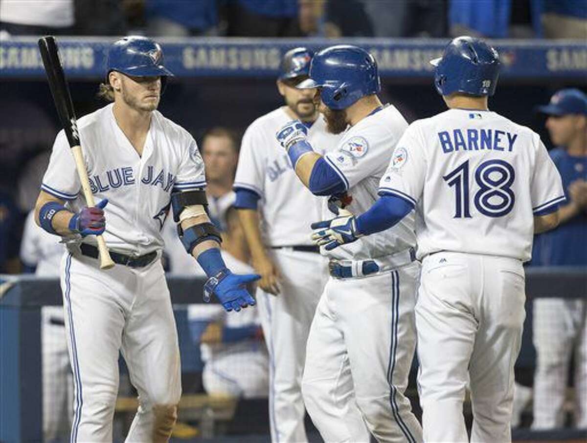 Toronto Blue Jays' Russell Martin, center, and Darwin Barney, right, are met by teammate Josh Donaldson after they both came into score on a double by Jose Bautista in the seventh inning of their baseball game against the Tampa Bay Rays in Toronto on Monday, Aug. 8, 2016. (Fred Thornhill/The Canadian Press via AP)