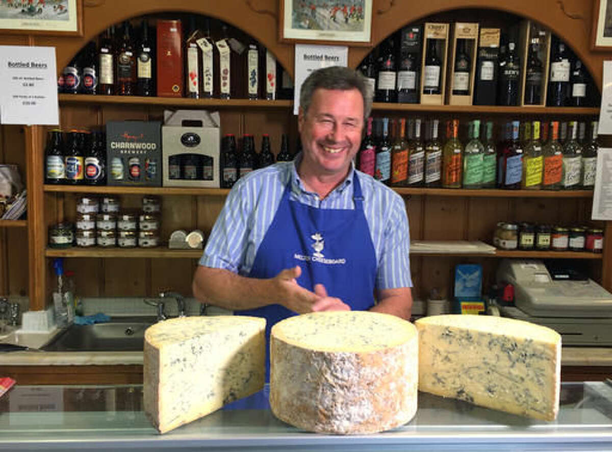 In this photo taken on Tuesday, Aug. 2, 2016, Tim Brown, the owner of the the Melton Cheeseboard, weighs out some cheese in his shop in Melton Mowbray, England. The marker of distinction for British food, the same kind that ensures Champagne can only come from the French region of the same name, is granted by the European Union and is now at risk after Britain voted to leave the 28-country bloc. The certificates, of which there are 73 across Britain for goods like Stilton cheese and Melton Mowbray pork pies, not only help farmers earn more but also shape rural communities’ identities. (AP Photo/Jonathan Shenfield)