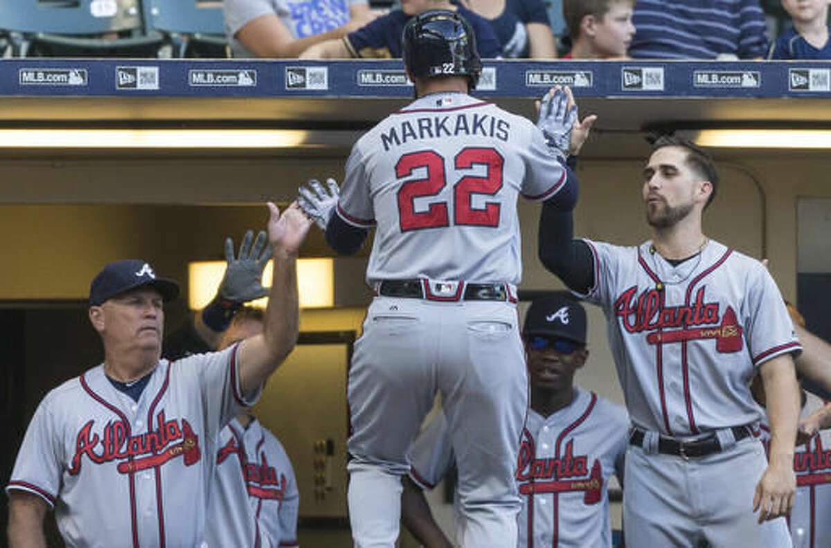 Atlanta Braves' Nick Markakis is greeted by teammates at the dugout after he hit a solo home run to right off of Milwaukee Brewers' Zach Davies during the second inning of a baseball game, Monday, Aug. 8, 2016, in Milwaukee. (AP Photo/Tom Lynn)