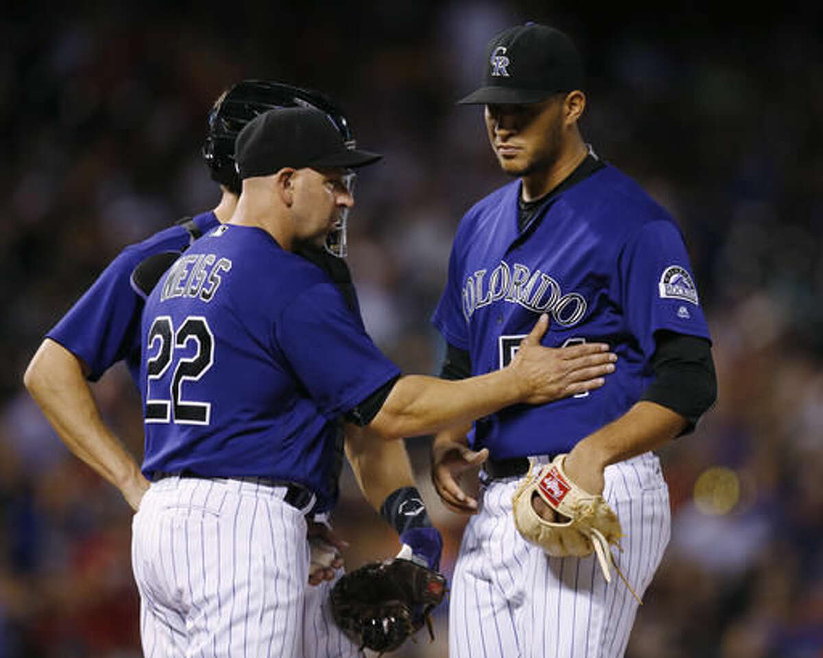 Colorado Rockies manager Walt Weiss, front left, pats relief pitcher Carlos Estevez as he is pulled from the mound after giving up a single to Texas Rangers' Elvis Andrus to bring in two runs in the ninth inning of a baseball game Monday, Aug. 8, 2016 in Denver. Colorado catcher Nick Hundley, back left, looks on. Texas won 4-3. (AP Photo/David Zalubowski)
