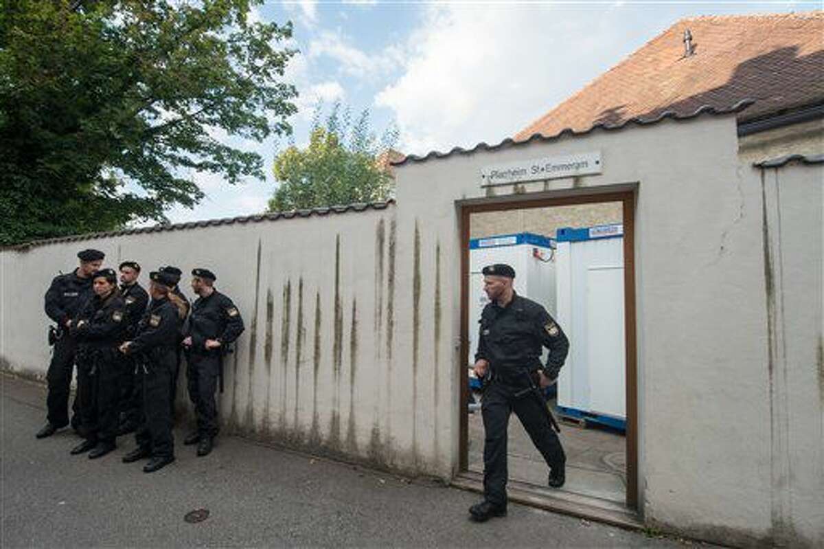 In this Aug. 8, 2016 picture police officers standing in front of the parish hall of St. Emmeram where refugees were living in Regensburg, Germany.The Roman Catholic diocese in Bavaria says it has ended a five-week protest at a church building by migrants from the Balkans. Some 50 migrants started camping out at Regensburg Cathedral early last month, demanding the right to stay in Germany and protesting the Balkan nations' designation as safe countries. A few days later, most moved to a vicarage across town. The diocese said the last 16 people were persuaded to leave Monday by police. (Armin Weigel/dpa via AP)