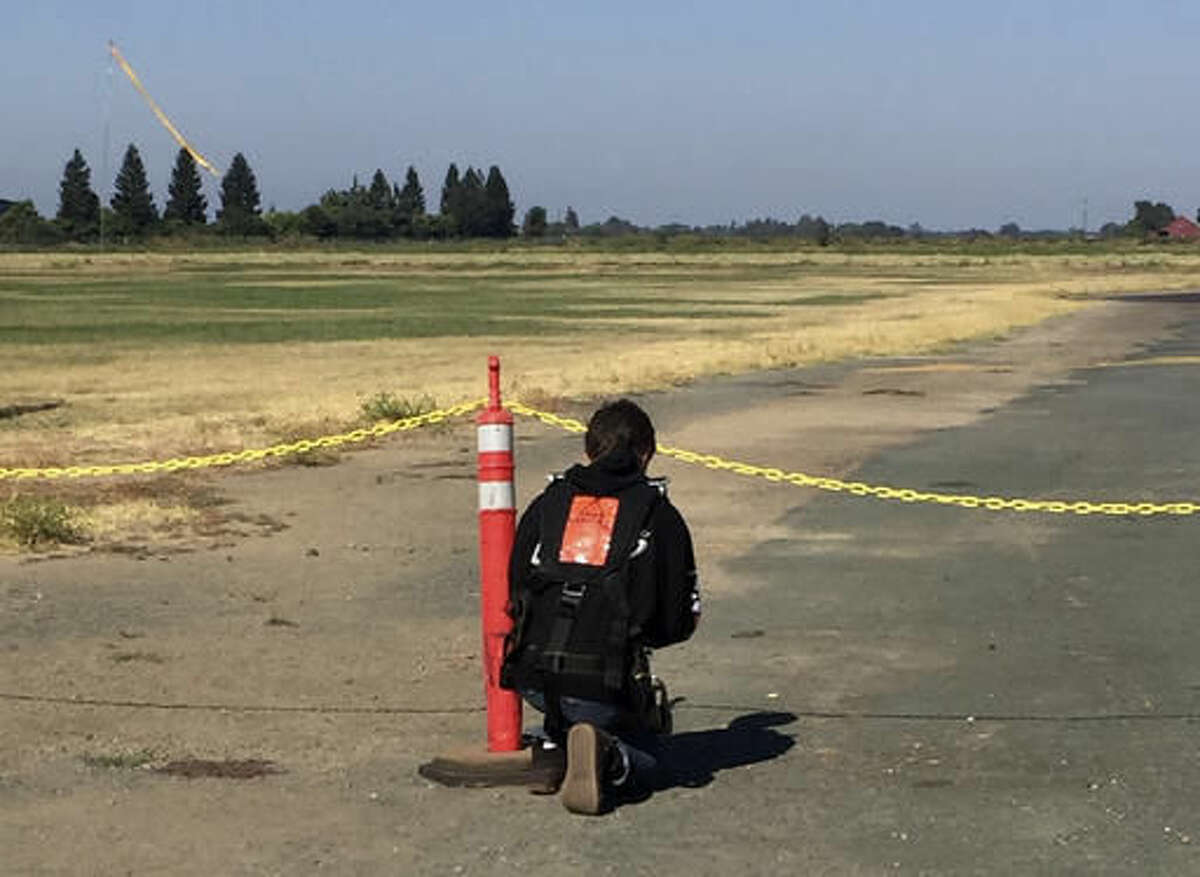 This Aug. 6, 2016 photo provided by Francine Salazar Turner shows her son Tyler Turner, 18, kneels on the edge of the runway and says a quick prayer prior to his fatal skydiving jump in Lodi, Calif. Salazar Turner said her teenage son was an adventurous spirit who was willing to try just about anything, including the jump that was on his bucket list of things to do in life. (Francine Salazar Turner via AP)