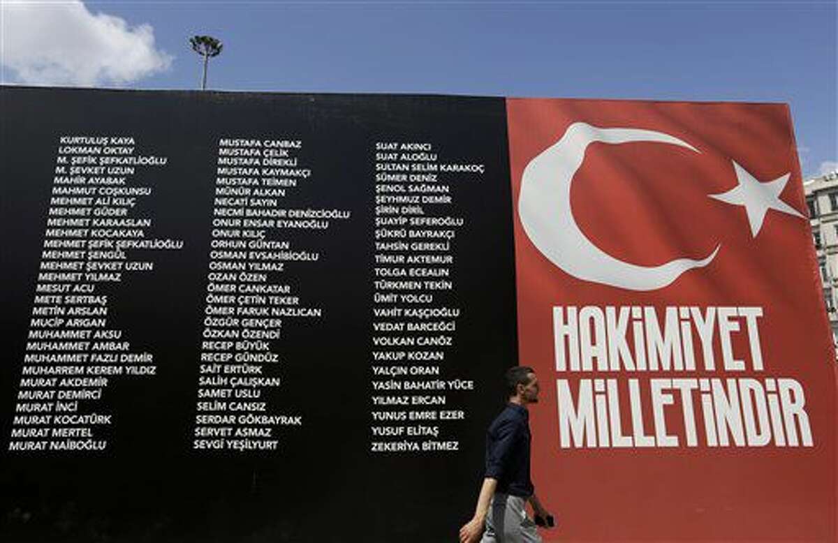 Un peatón pasa junto a un cartel que recuerda a los caídos durante el intento de golpe de Estado del 15 de julio, el lunes 8 de agosto de 2016. Bajo el símbolo de la bandera turca pone "la soberanía pertenece al pueblo". (AP Foto/Thanassis Stavrakis)