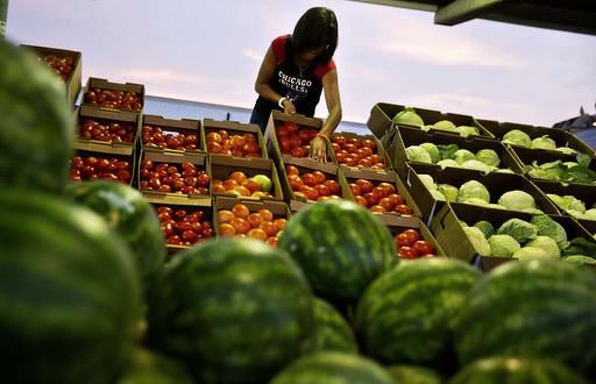 FILE - In this Saturday, June 6, 2015, file photo, Ailyn Lopez sets up a display of tomatoes while helping out on her family's stand at the Atlanta Farmers Market in Atlanta. On Tuesday, Aug. 9, 2016, the Commerce Department releases wholesale trade inventories for June. (AP Photo/David Goldman, File)