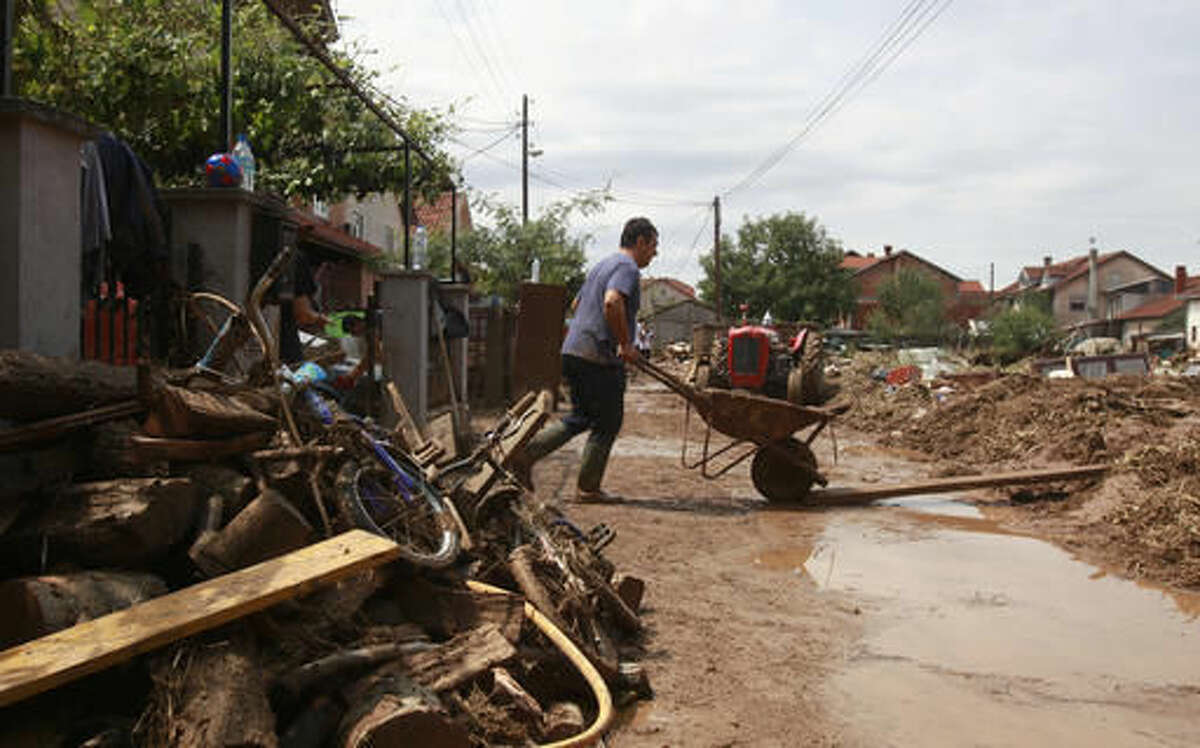A man pushes a wheelbarrow with mud from his flooded house after a storm, in the village of Stajkovci, just east of Skopje, Macedonia, on Monday, Aug. 8, 2016. Macedonia's government declared a state of emergency Sunday in parts of the capital hit by torrential rain and floods that left at least 21 people dead, six missing and dozens injured, authorities said.(AP Photo/Boris Grdanoski)