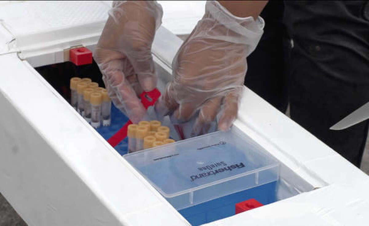 In this July 27, 2016 handout image from a Vayu, Inc. video, a laboratory worker unpacks blood and stool samples collected from rural Madagascar villagers at Stony Brook University's Madagascar-based Centre ValBio research station after they were delivered in a test drone flight from Raomafana, a five-to-nine hour distance on foot. The Long Island based university, which has conducted research in the Indian Ocean island nation off East Africa for nearly three decades, has teamed up with a Michigan drone maker Vayu, Inc. to deliver laboratory samples and distribute medicine to rural villages in a more timely fashion. Stony Brook officials say the quick delivery system could ultimately help save lives.(Stony Brook University/Vayu, Inc. via Associated Press)