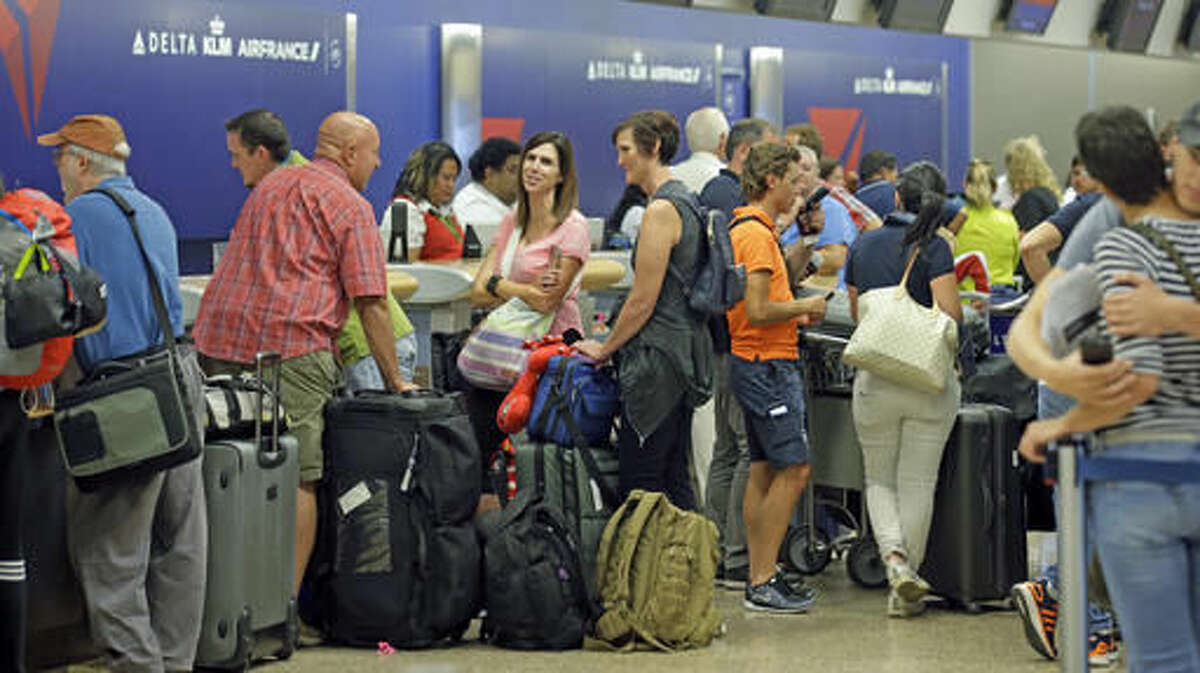Passengers stand in line after Delta Air Lines flights resumed Monday, Aug. 8, 2016, in Salt Lake City, following a computer outage. Delta Air Lines delayed or canceled hundreds of flights Monday after its computer systems crashed, stranding thousands of people on a busy travel day. (AP Photo/Rick Bowmer)