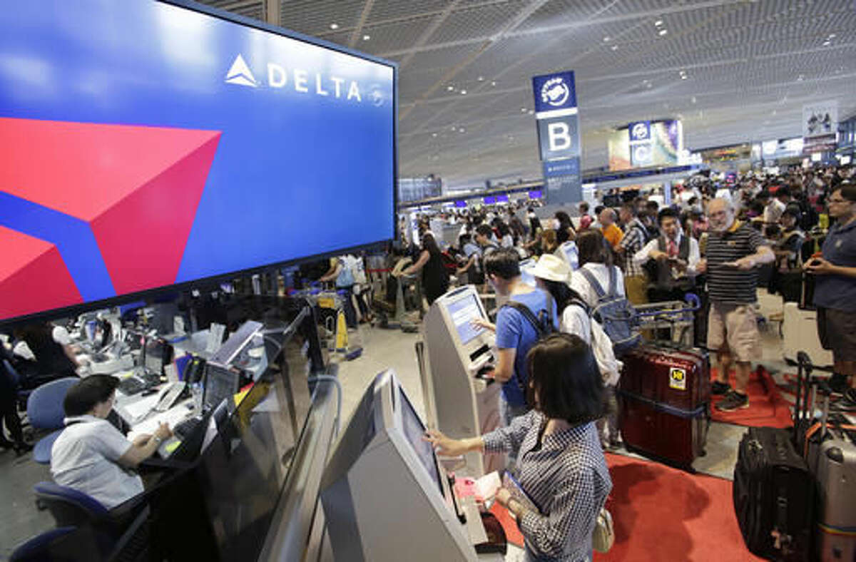 Passengers check in at the Delta Air Lines counter at Narita international airport in Narita, east of Tokyo, Tuesday, Aug. 9, 2016. More than 1,000 people spent the night at the Narita airport because of a computer shutdown that halted Delta Air Lines flights worldwide. (AP Photo/Shizuo Kambayashi)