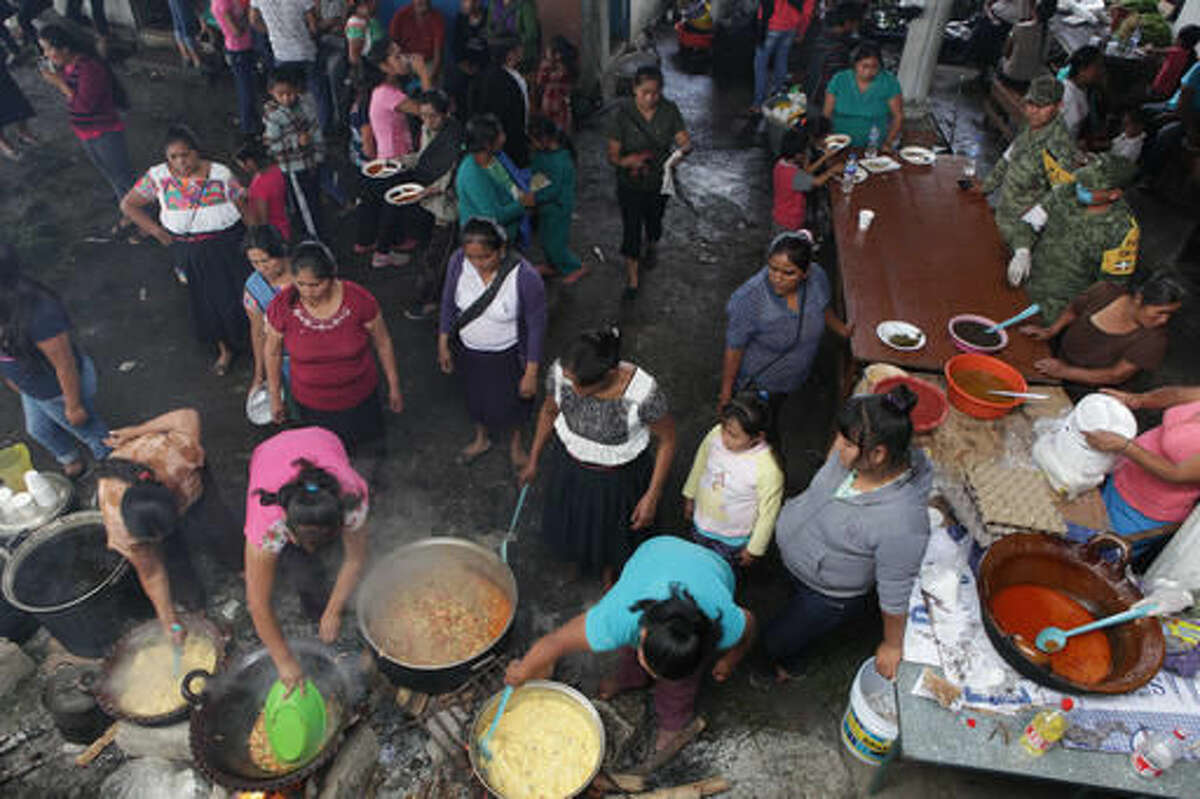 Women prepare food for people who are in a temporary shelter in Papatlazolco, Mexico, Monday, Aug. 8, 2016. Mountain communities in two Mexican states are recovering from weekend mudslides that killed dozens during heavy rains brought by remnants of Hurricane Earl. (AP Photo/Pablo Spencer)