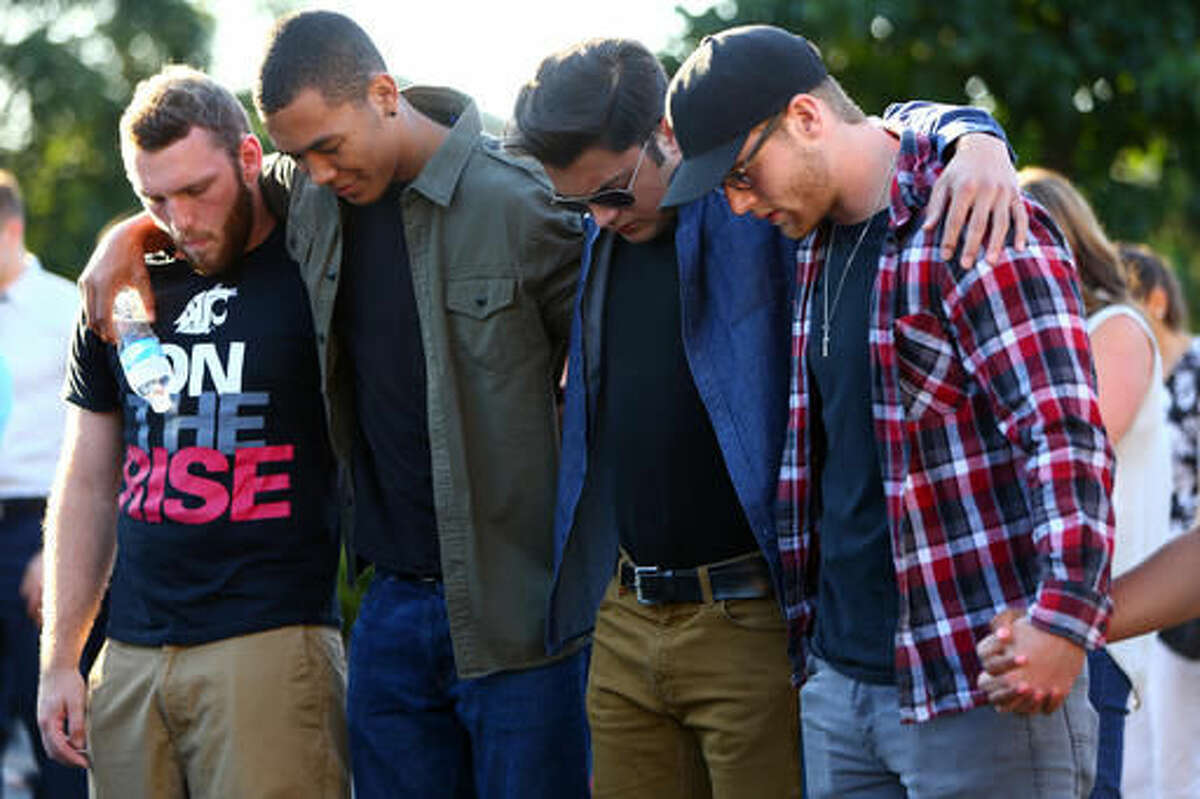 FILE--In this July 31, 2016, file photo, friends of victims huddle together during a prayer as hundreds gather for a community vigil for the victims of a shooting at a house party, killing three teenagers and wounding one. Young people attending the party where a gunman opened fire frantically told a dispatcher their friends were bleeding to death according to newly released tapes of the calls Tuesday, Aug. 9, 2016. (Genna Martin/seattlepi.com via AP, file)