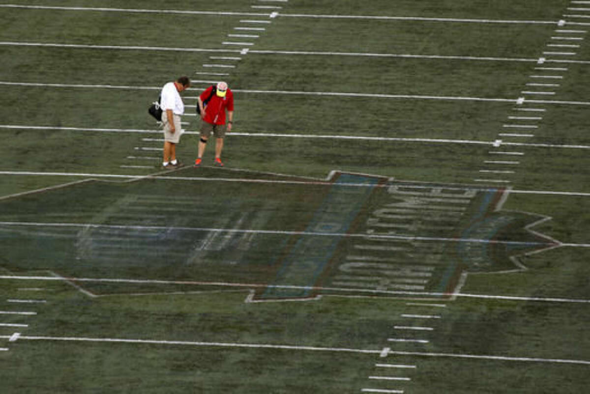 The damaged field at Tom Benson Hall of Fame Stadium is inspected after the preseason NFL football game was cancelled due to unsafe field conditions caused by the painted logo at midfield, Sunday, Aug. 7, 2016, in Canton, Ohio. (AP Photo/Gene J. Puskar)