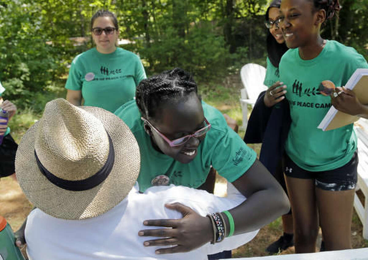 In this Aug. 4, 2016 photo, second-year camper, Ludya, hugs Tim Wilson, special advisor, to the Seeds of Peace camp in Otisfield, Maine. The nation's divide has become bad enough that a camp created to help Arab and Israeli teens find common ground is putting an emphasis on hatred and violence in the U.S. Seeds of Peace, a lakeside camp in the woods of Maine, has embarked on a pilot program this summer with teenagers from Los Angeles, Chicago and New York City. (AP Photo/Elise Amendola)