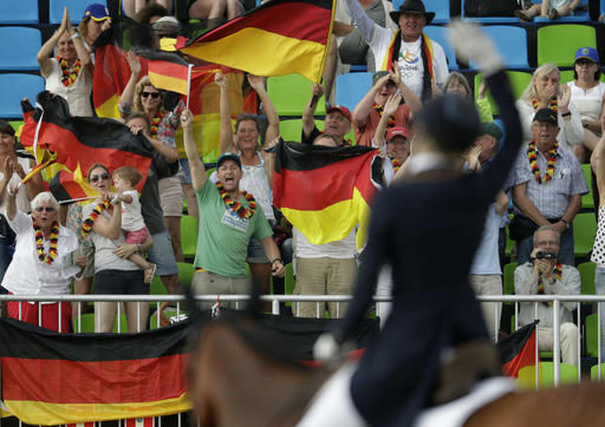 Fans cheer for Ingrid Klimke, in foreground, of Germany, and her horse Hale-Bob Old after they competed in the equestrian eventing dressage competition at the 2016 Summer Olympics in Rio de Janeiro, Brazil, Sunday, Aug. 7, 2016. (AP Photo/John Locher)