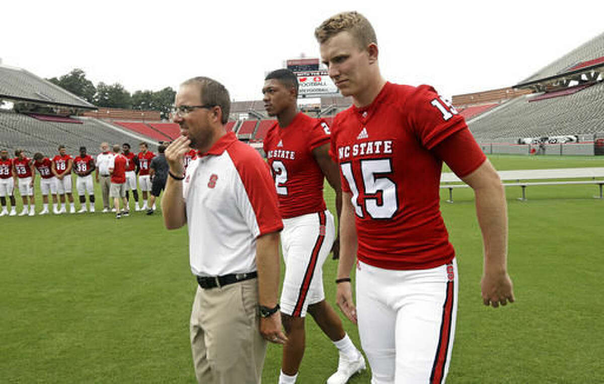 North Carolina State offensive coordinator Eli Drinkwitz, left, leads quarterbacks Ryan Finley (15) and Jalan McClendon off the field during the NCAA college football team's media day in Raleigh, N.C., Sunday, Aug. 7, 2016. (AP Photo/Gerry Broome)