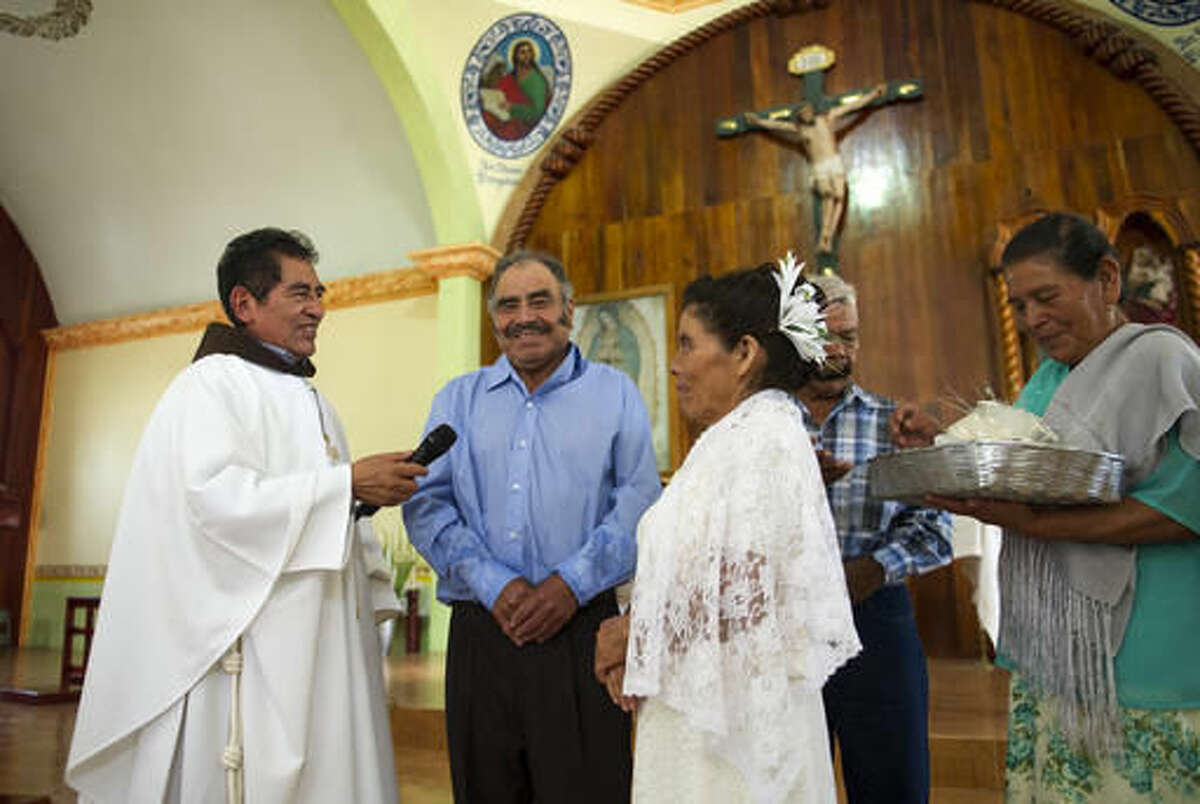 In this July 23, 2016 photo, Francisca Santiago, 65, and her lifelong partner Pablo Ibarra, 75, crack a smile as they exchange wedding vows at the church in Santa Ana, in the Mexican state of Oaxaca. The Rev. Domingo Garcia Martinez performed Ibarra and Santiago's wedding in front of about 250 family and friends. (AP Photo/Nick Wagner)