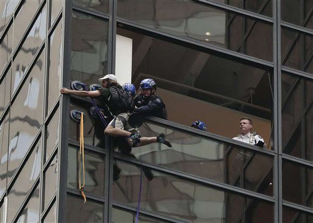 Policías batallan para meter por una ventana a un hombre que estaba escalando la Torre Trump, el miércoles 10 de agosto de 2016, en Nueva York. El edificio de 58 pisos es sede de la oficina de campaña del candidato presidencial republicano Donald Trump, quien además vive en el inmueble. (AP Foto/Julie Jacobson)