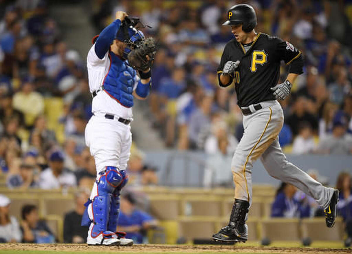Pittsburgh Pirates' Jordy Mercer, right, scores on his solo home run as Los Angeles Dodgers catcher Yasmani Grandal stands at the plate during the seventh inning of a baseball game, Friday, Aug. 12, 2016, in Los Angeles. (AP Photo/Mark J. Terrill)