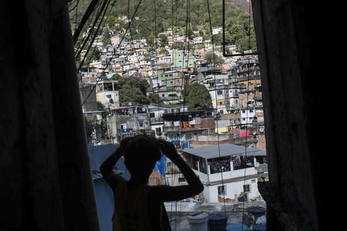 Eric Marques adjusts his sunglasses as he walks down the Rocinha slum on his way to surf at the nearby Sao Conrado beach in Rio de Janeiro, Brazil, Saturday, Aug. 13, 2016. The children Rio de Janeiro’s biggest slum have little. But they border the water. While some of the world’s top Olympic athletes compete in nearby Guanabara Bay, they attend a surfing school in the heavily polluted waves and dream that maybe, they’ll be good enough to compete on their sport’s biggest stage one day. (AP Photo/Felipe Dana)