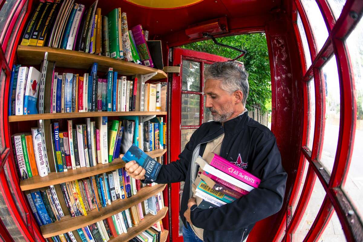 A visitor browses books in an honor library inside a converted red telephone box on Lewisham Way in London on Aug. 3, 2016.