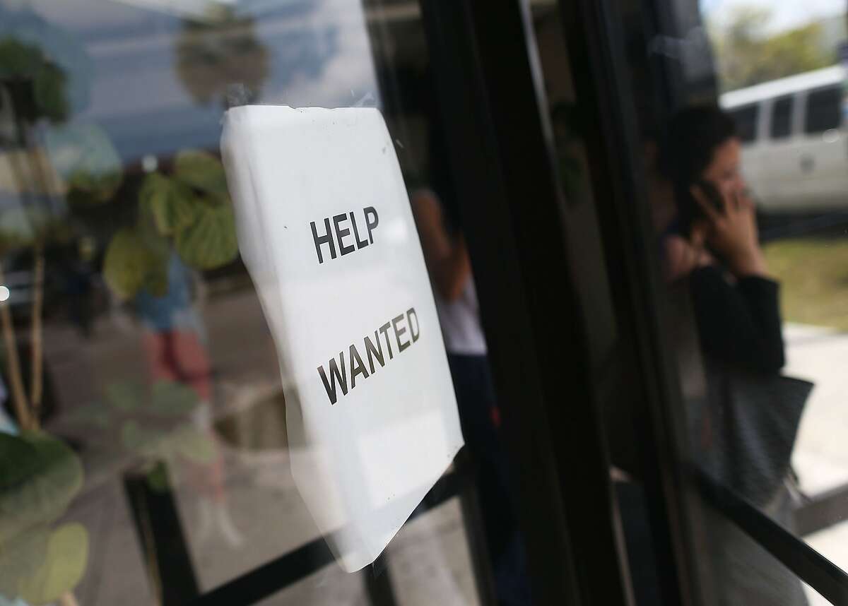 A help wanted sign is seen in the window of a business.