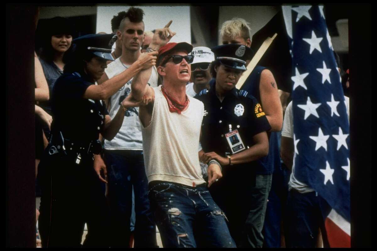 AUGUST 1984: Female police officers restrain radical Gregory Johnson after his flag-burning demonstration to express anger against President Ronald Reagan's policies during the Republican National Convention. (Photo by David Leeson/Image Works/Image Works/The LIFE Images Collection/Getty Images)