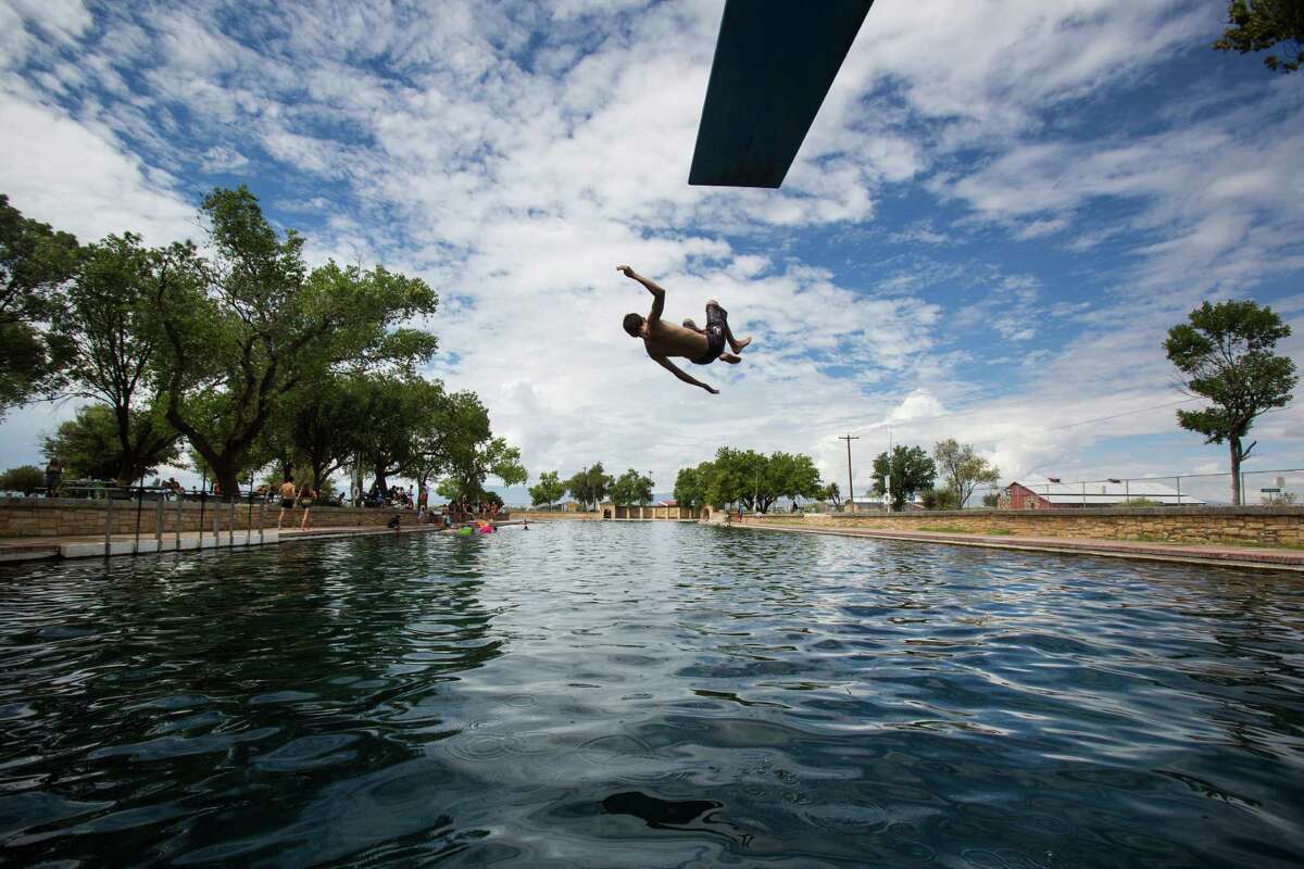 A boy jumps off the diving board into 30 feet of water at the natural spring pool at the Balmorhea State Park on Thursday, August 18, 2016. The rise of fracking nearby the town has some community members worried about their drinking water and natural springs, which serve as a popular tourism destination helping drive the town's economy.