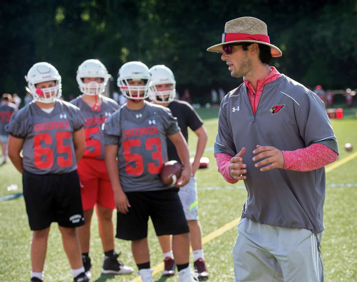 Head coach John Marinelli gives his team instructions Friday during the first day of practice for the Greenwich High football team at Greenwich High School. Below, Tyler Farris runs a pass route during Friday’s practice.