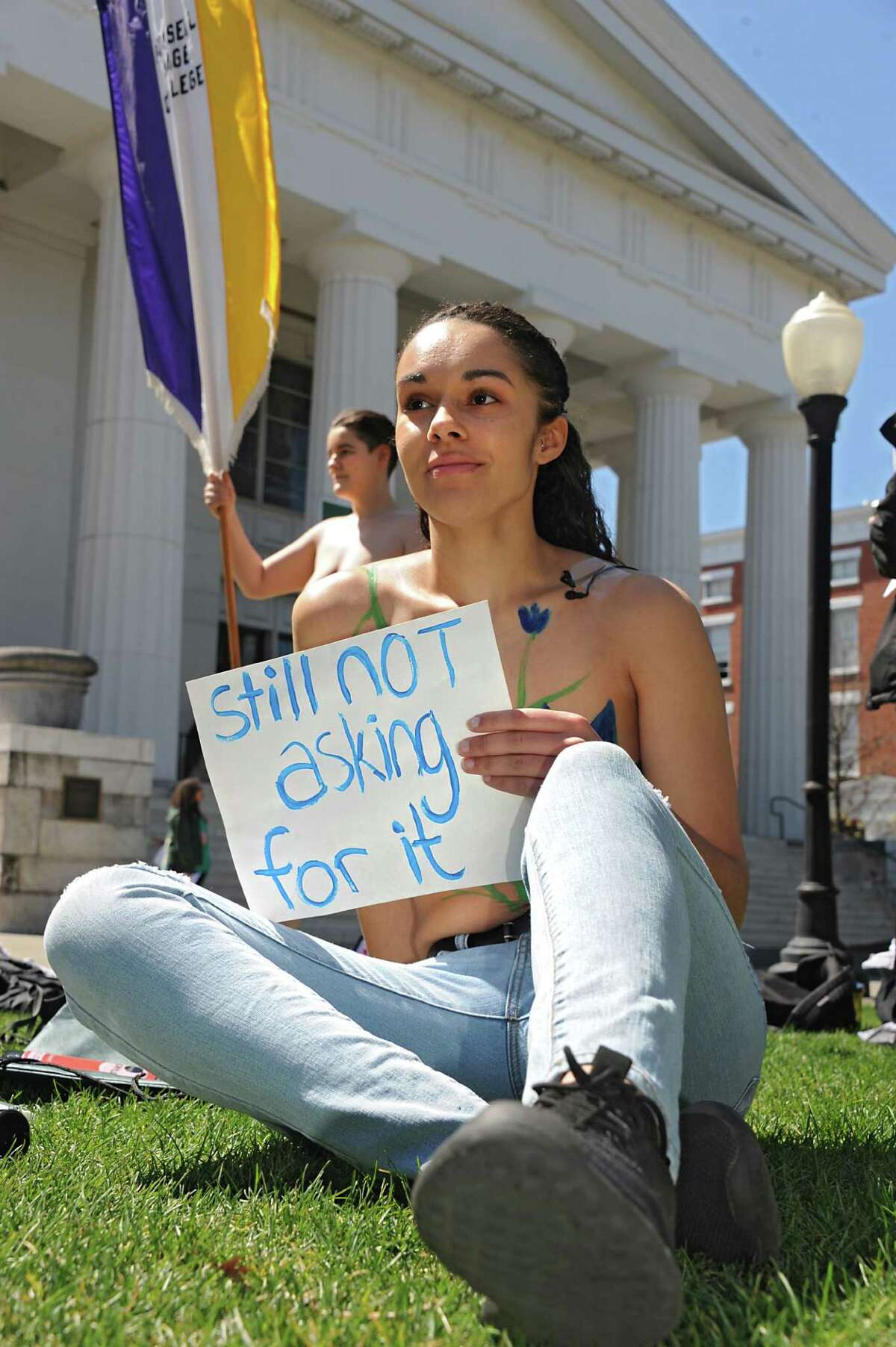 Katie Giarratano, a senior Russell Sage student from Liberty, N.Y., holds a sign as students upset by police treatment of Cedar Brock, behind her, hold a topless protest in Sage Park on the Russell Sage College campus Wednesday, April 120, 2016 in Troy, N.Y. A school security officer approached Cedar, a student who identifies as androgynous, who was sunbathing topless in a public park that fronts the campus. (Lori Van Buren / Times Union)