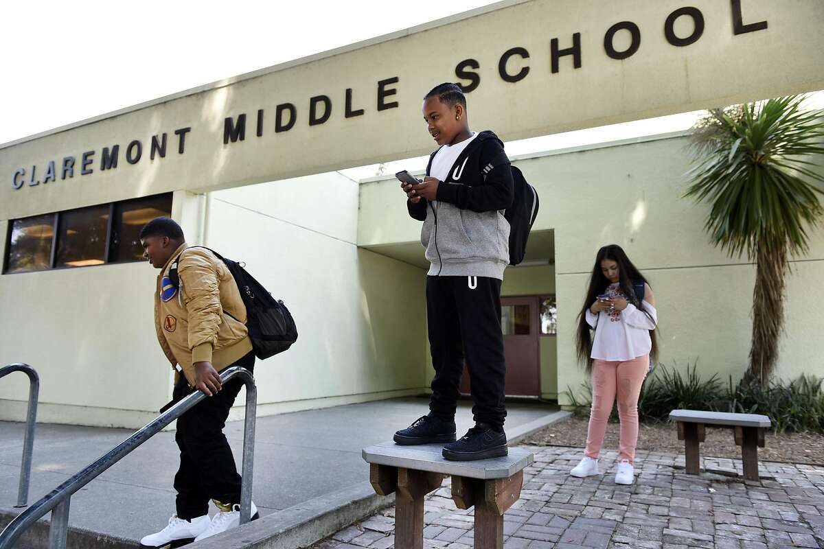 Seventh grade students Ahmari Prince, left, Antoine Chatman and Alyssa Algeria hang out in front of the office after their first day back at Claremont Middle School in Oakland, CA Monday, August 22, 2016.